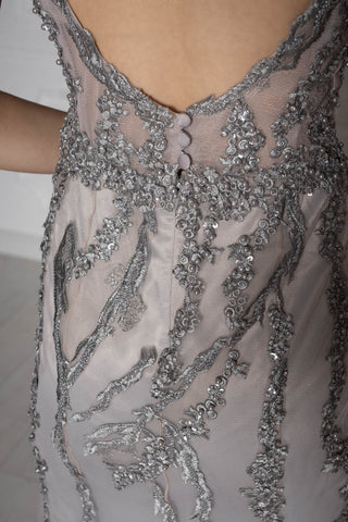 Silver beaded evening gown with plunging V-neckline, sleeveless design, and mermaid silhouette.